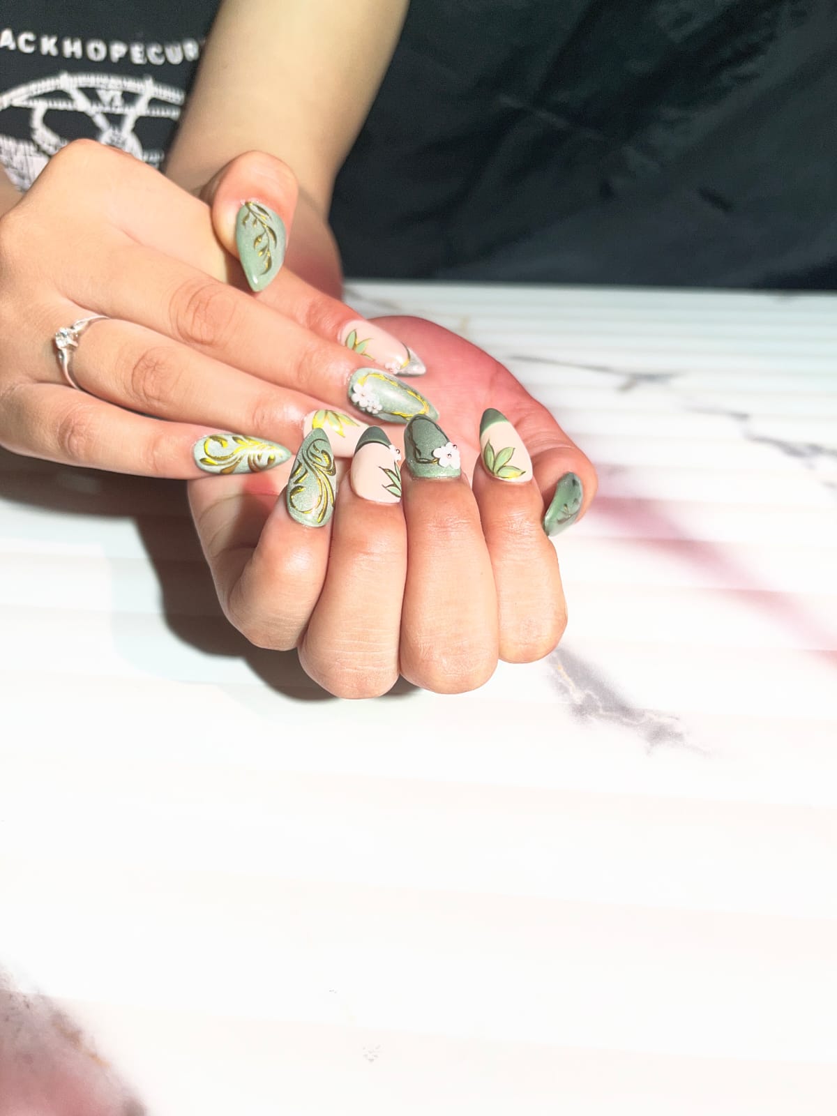 Decorative green, gold and floral nail art.